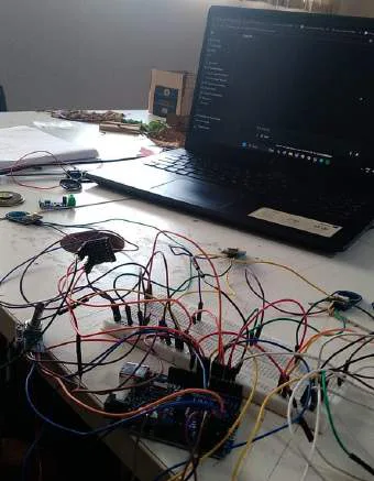 Breadboard, sensors and wiring next to a laptop running the code